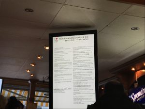 Foto av ljustavla med meny på, upphängd i taket på aktuell restaurang.